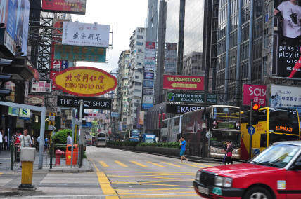 Hong Kong red taxi on busy street - iconic urban transportation with driver and passenger
